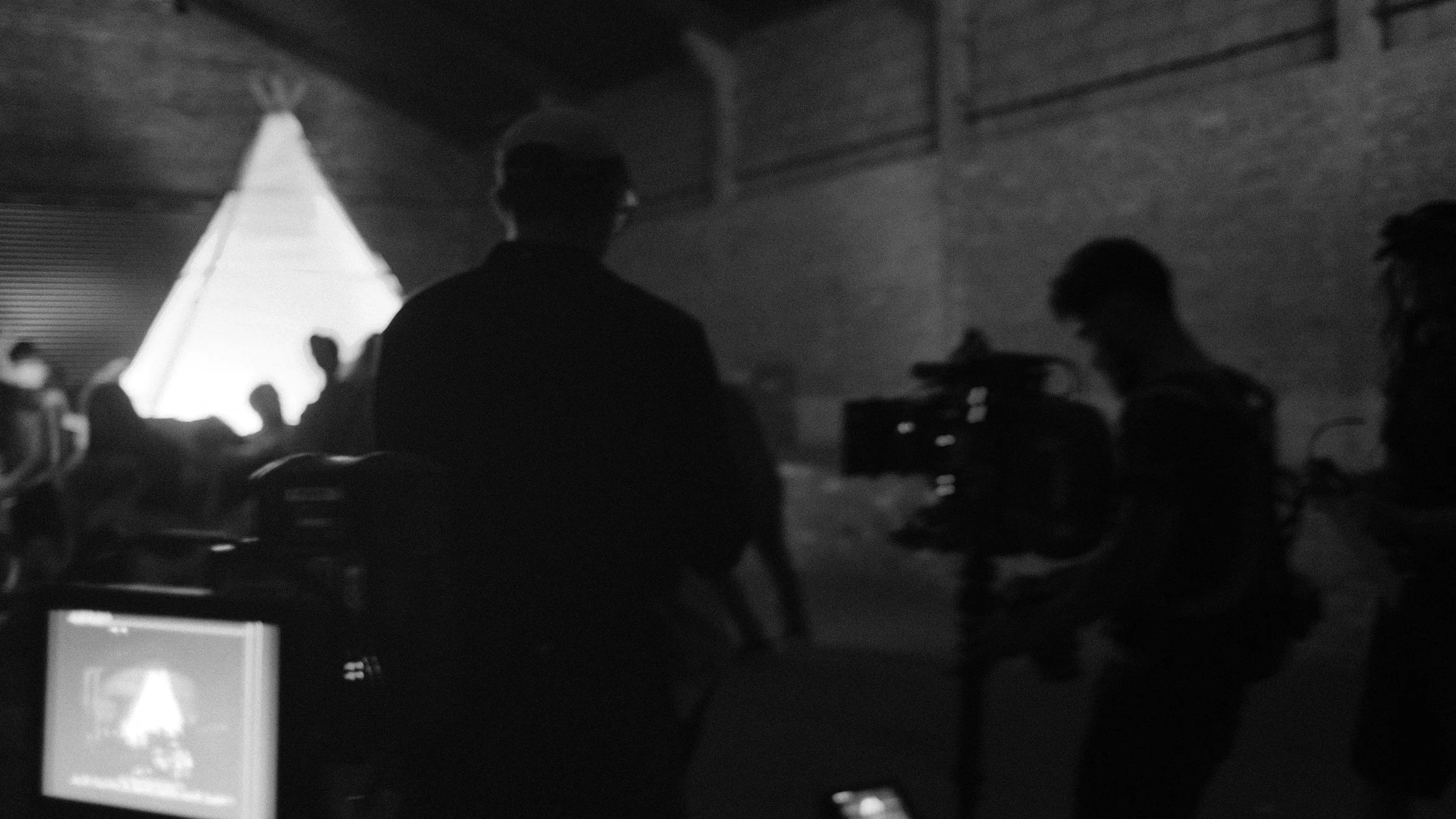 Crew members and a camera silhouetted around a lit set