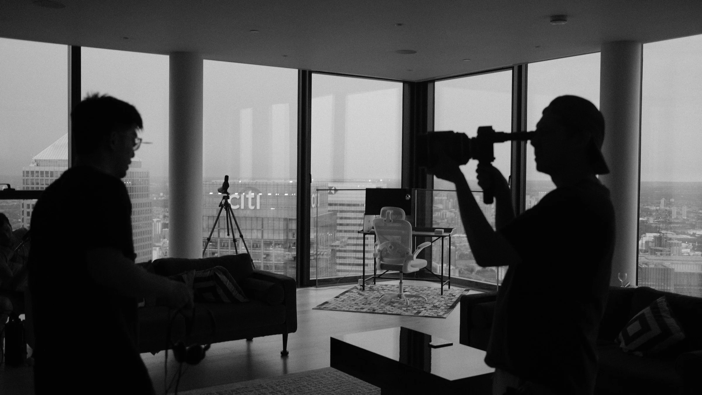 Camera operator filming a seated subject in a high-rise interior