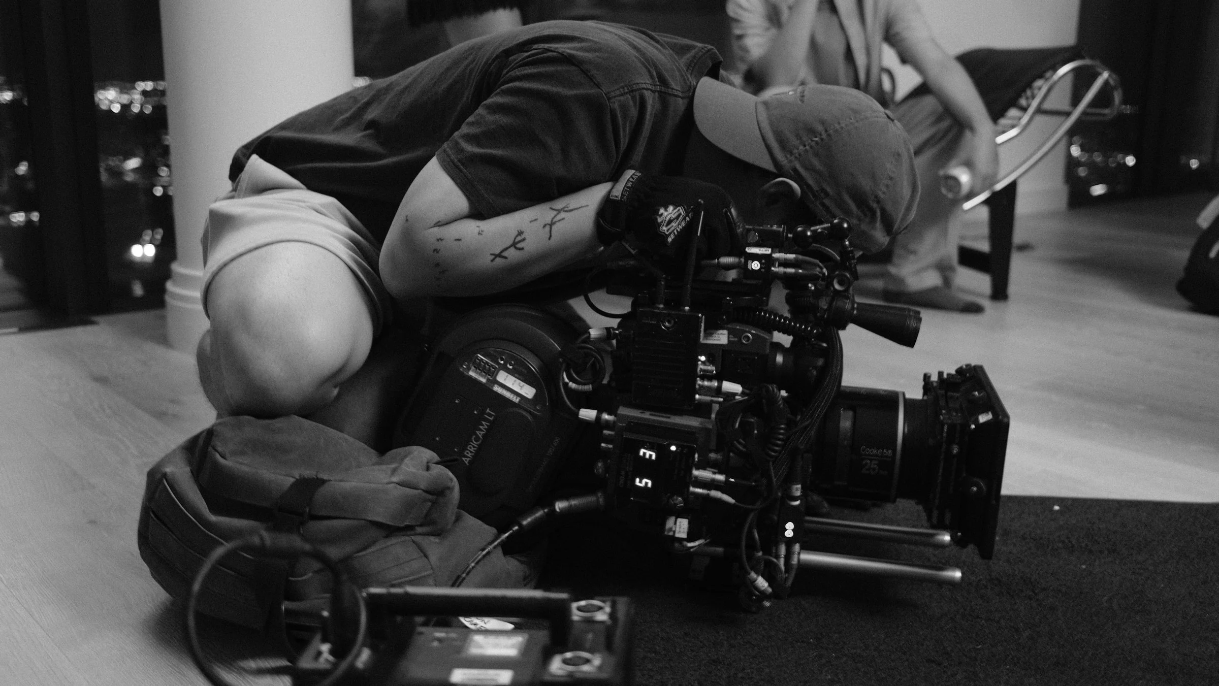 Crew member adjusting a cinema camera on the floor