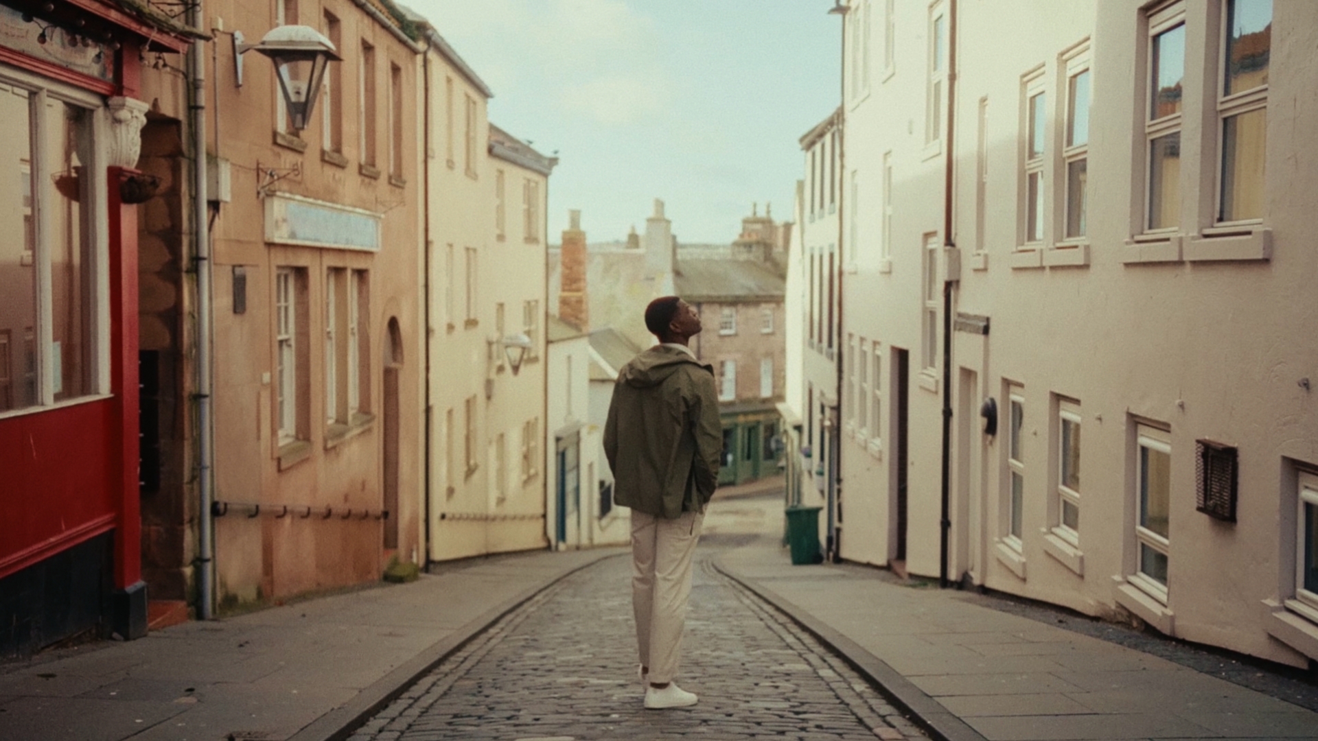 Man stands in-between two walls facing the river in a seaside town