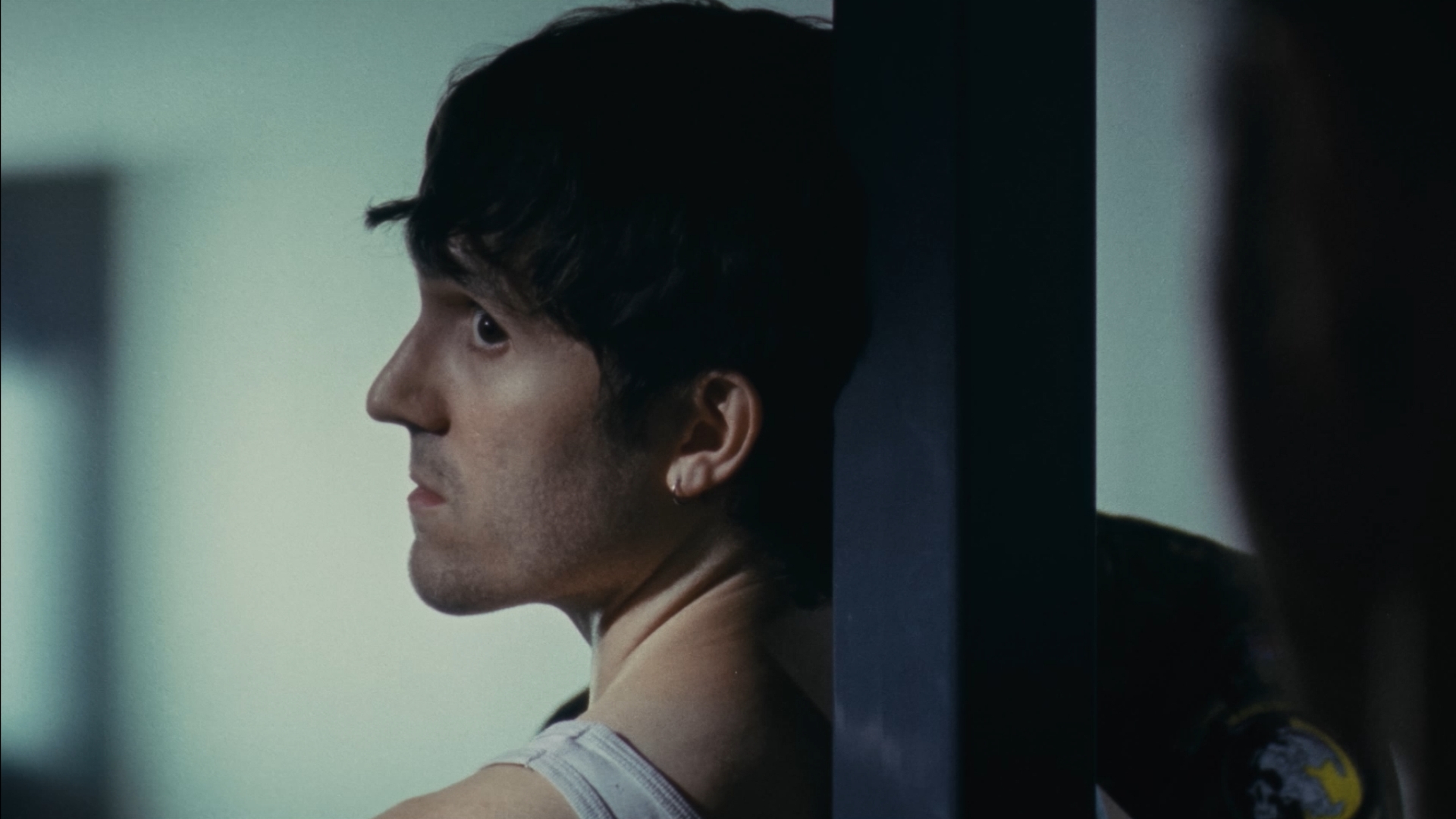 A young man seen in profile through reflective glass in First Cut